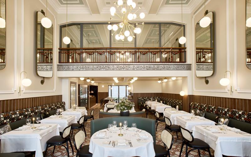 Spacious restaurant interior with chandelier, patterned banquette seating, and elegant dining setup at ON Residence