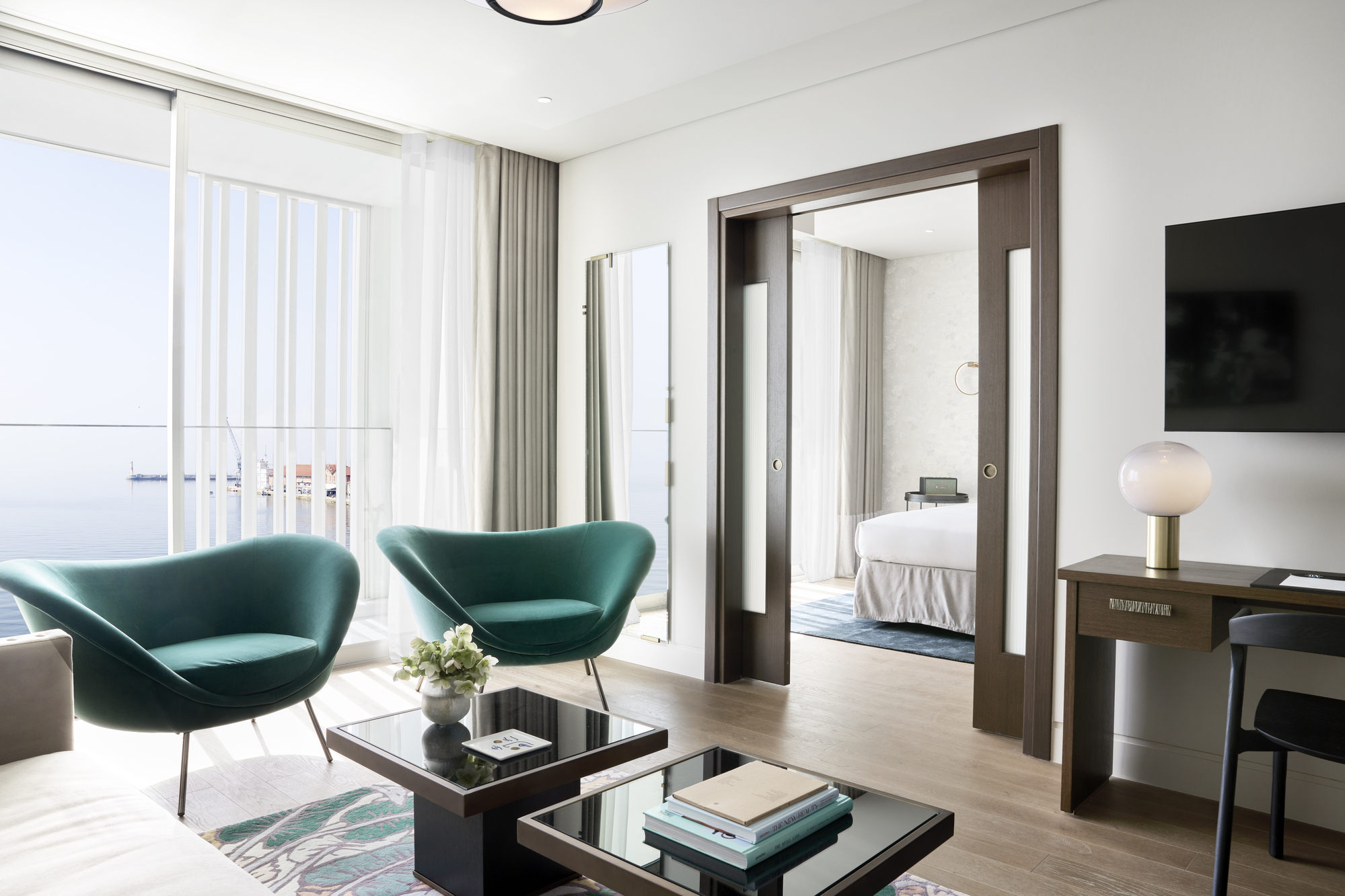 
Bright living room in Olympos suite with teal armchairs, tables and sea view balcony at ON Residence Hotel
