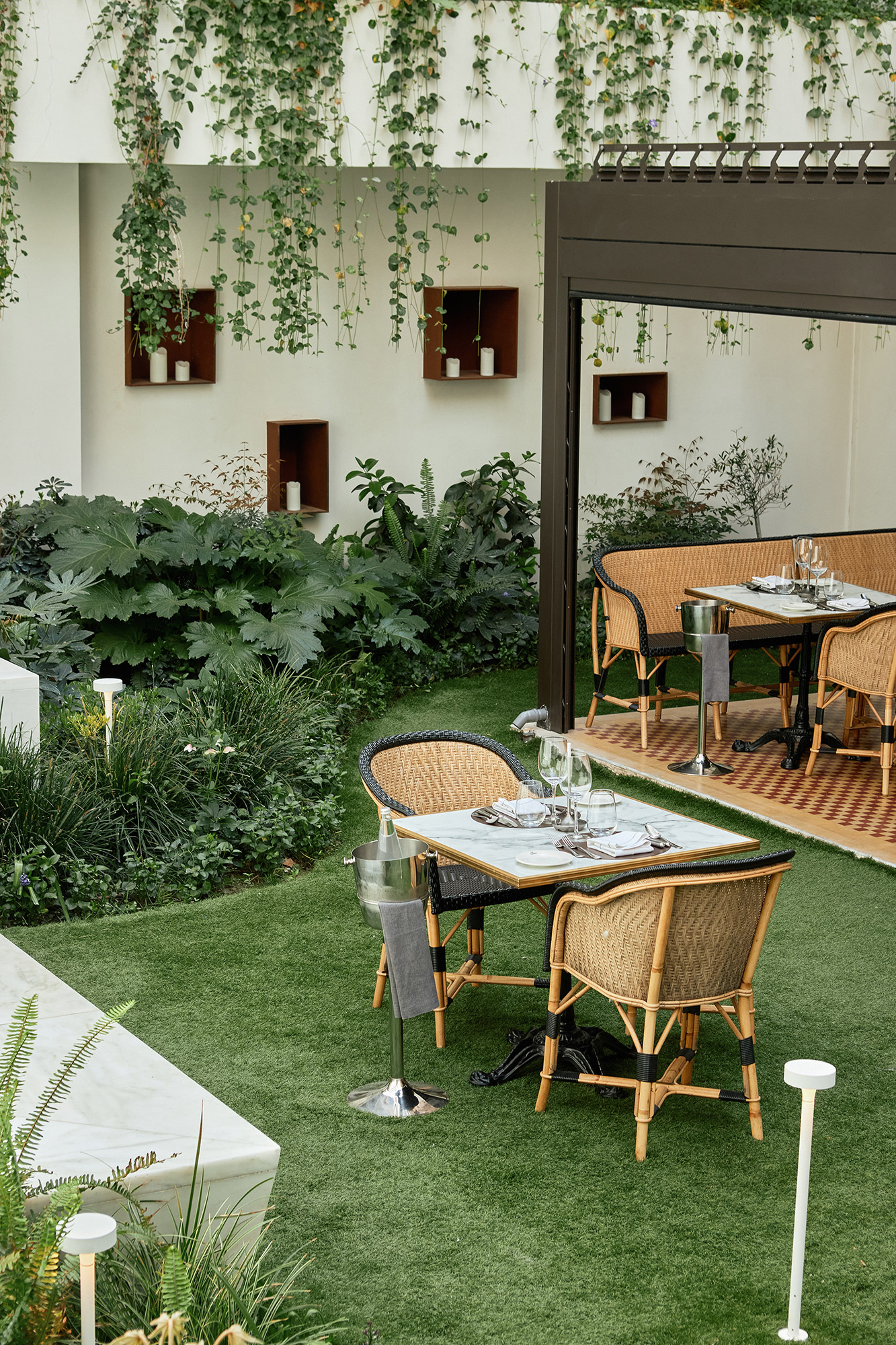 
Olympos Naousa restaurant garden with dining tables surrounded by lush greenery at ON Residence
