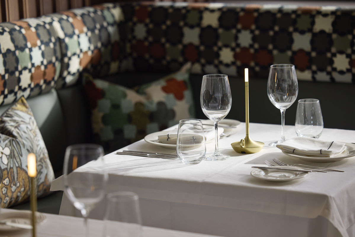 
Restaurant table setting with wine glasses, white tablecloth and golden candlelight at ON Residence Hotel