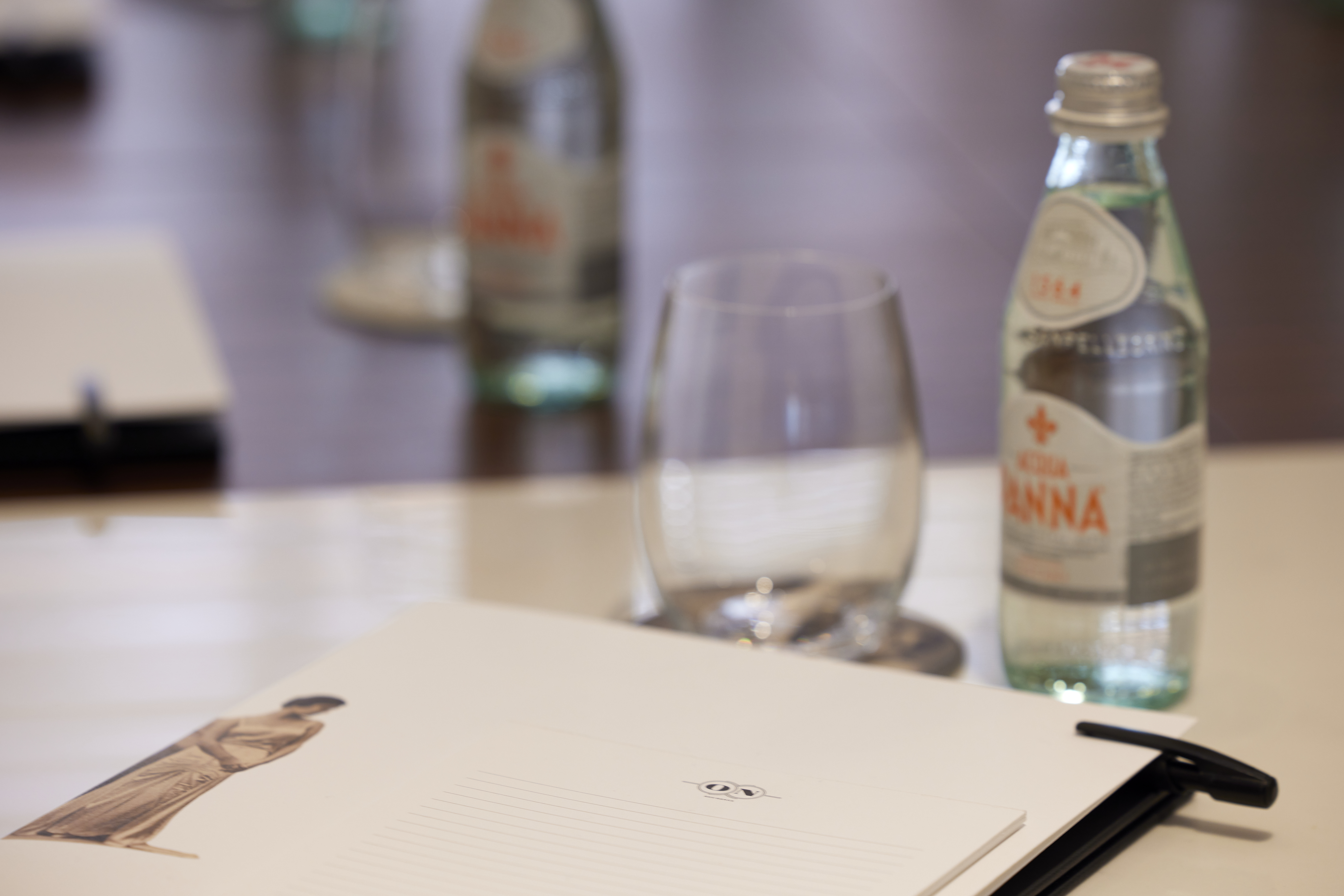 
Close-up of meeting room setup with notepad, glass and water bottle at ON Residence