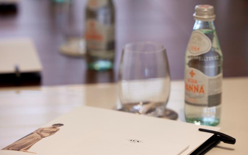 Close-up of meeting room setup with notepad, glass and water bottle at ON Residence