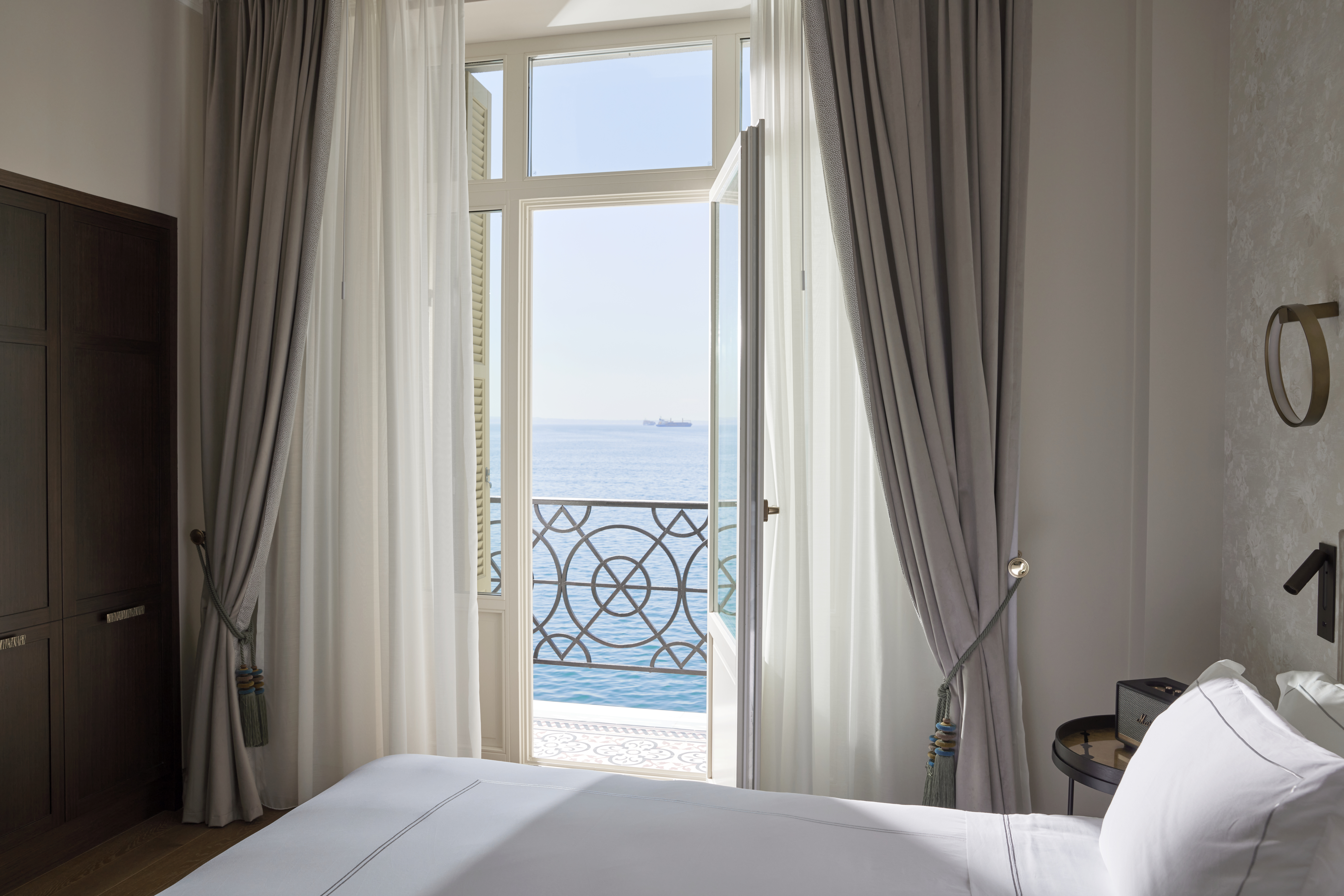
Sea view bedroom in Méditerranée grand suite with elegant curtains, balcony doors and modern decor
