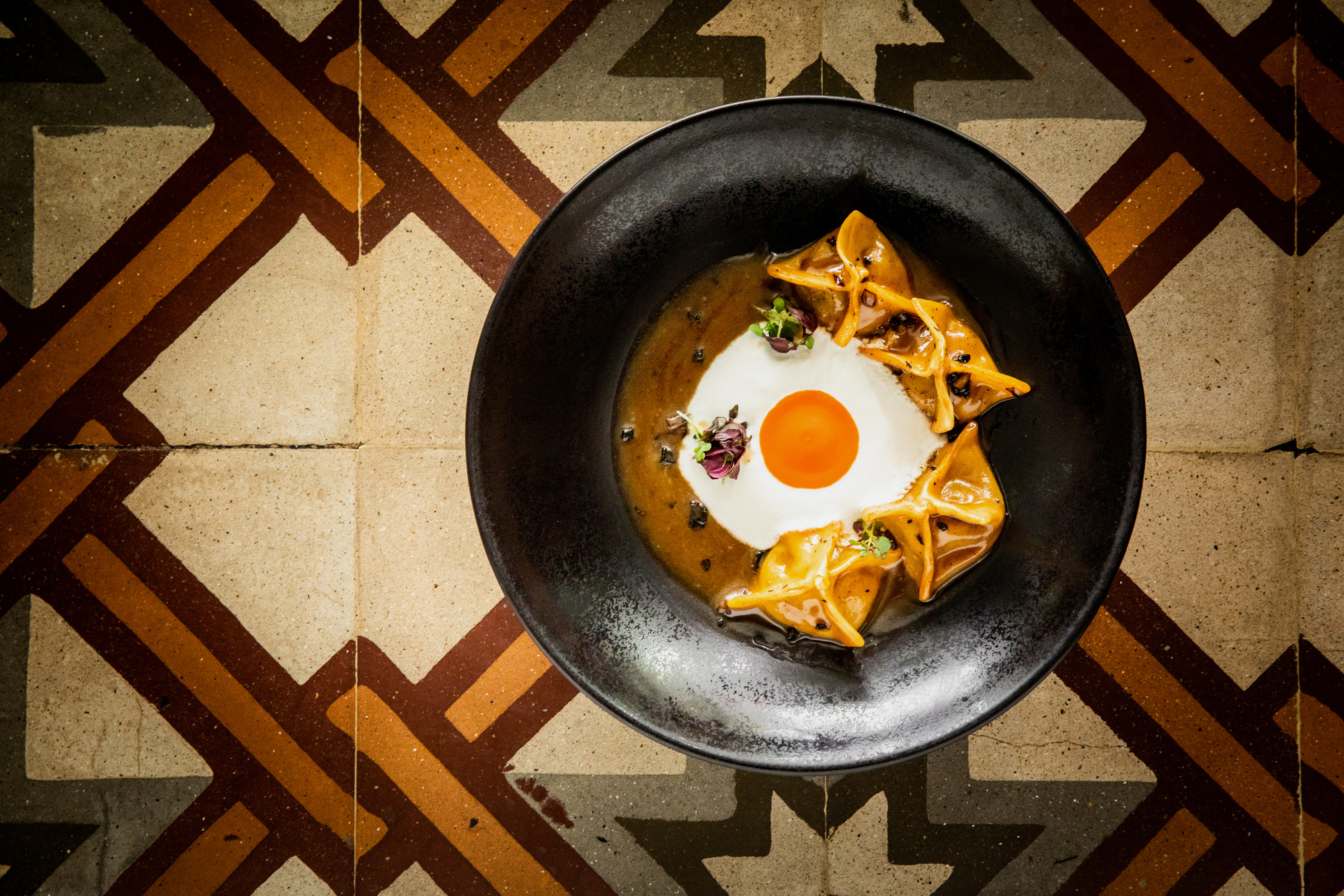 
Handmade manti dumplings in rich sauce with fried egg yolk centerpiece at Olympos Naousa Restaurant