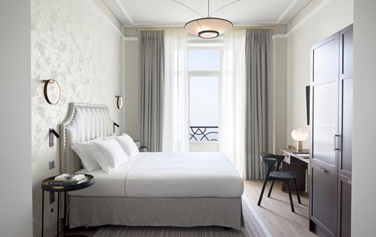 Junior suite seafront with king bed, balcony access, modern desk and elegant decor at ON Residence Hotel