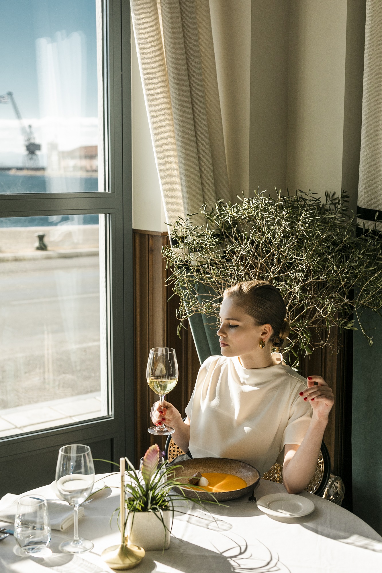 
Elegant woman enjoying wine and fine dining by the window with sea view at ON Residence Hotel