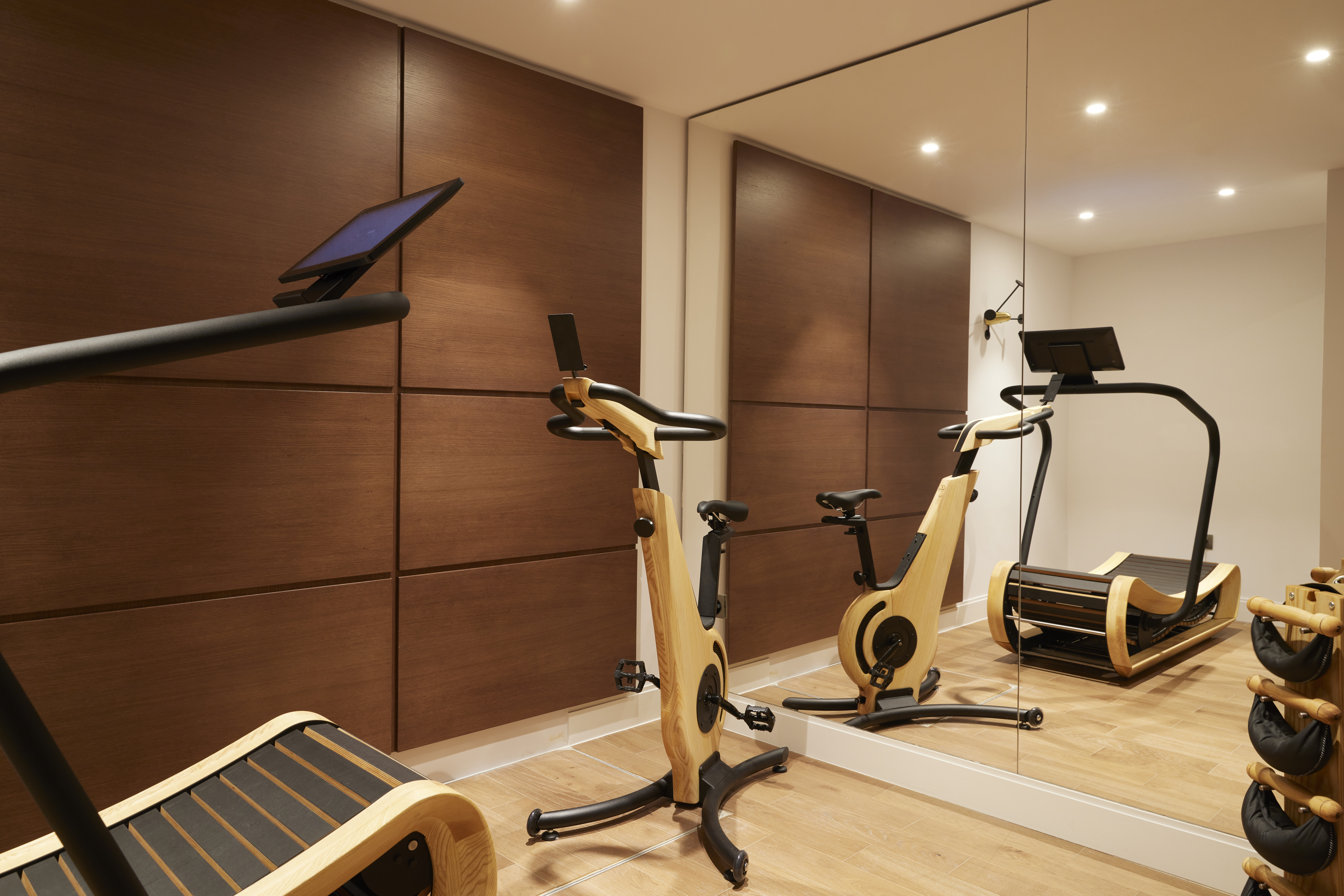 
Modern fitness room with wooden exercise bike, treadmill and mirrored wall at ON Residence Hotel